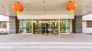 Een hotelentree met een draaideur, glazen deuren en twee oranje lantaarns.