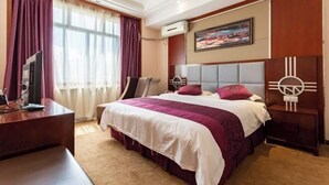 Een hotelkamer met een groot bed, een bureau met een computer, een stoel en een televisie.