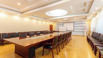 A conference room with a long table, chairs, a projector screen, and a whiteboard.