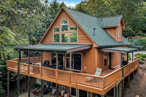 Une cabane en bois dotée d’un balcon, de grandes fenêtres et d’une terrasse couverte.