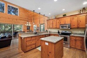 Une cuisine spacieuse dotée de meubles en bois, de plans de travail en granit, d’appareils électroménagers en acier inoxydable et d’un grand îlot central.
