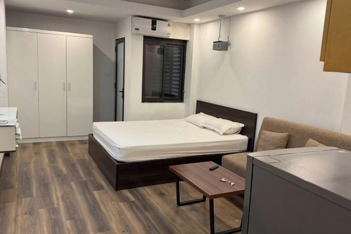 A compact bedroom with a bed, bedside table, wardrobe, and a small desk.