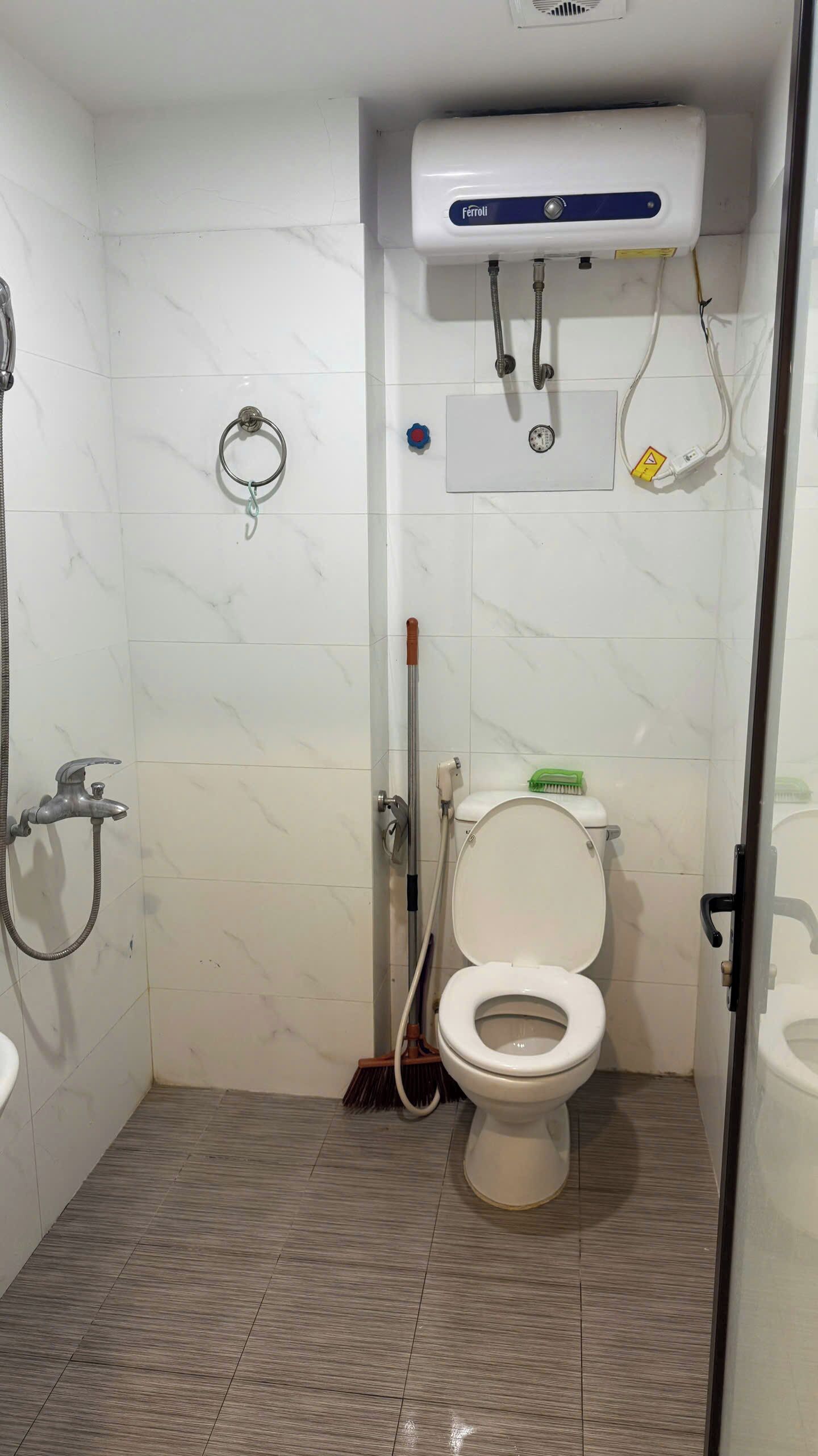 Pieni kylpyhuone, jossa on wc, suihku ja käsienkuivaaja.