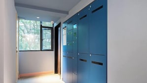 A hallway with blue lockers, a window with a view of trees, and a door leading to another room. - HanTing Hotel (Xiamen Wenzao The MixC) (Xiamen)