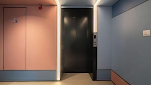A modern elevator with a control panel, a door with a safety sign, and a wall with a light strip. - HanTing Hotel (Xiamen Wenzao The MixC) (Xiamen)