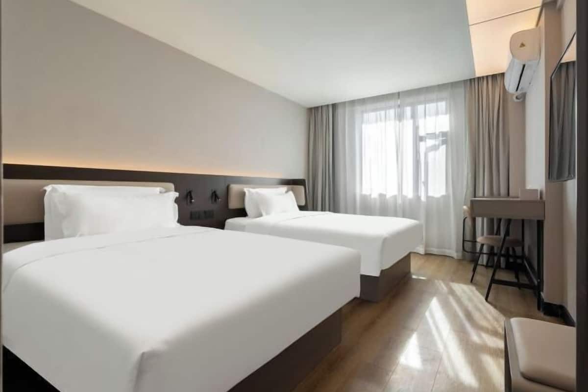 Une chambre d’hôtel avec deux lits, un bureau et une chaise.