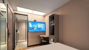 A hotel room with a bed, a desk, a chair, a television mounted on the wall, and a door leading to another room. - HanTing Hotel (Xiamen Wenzao The MixC) (Xiamen)