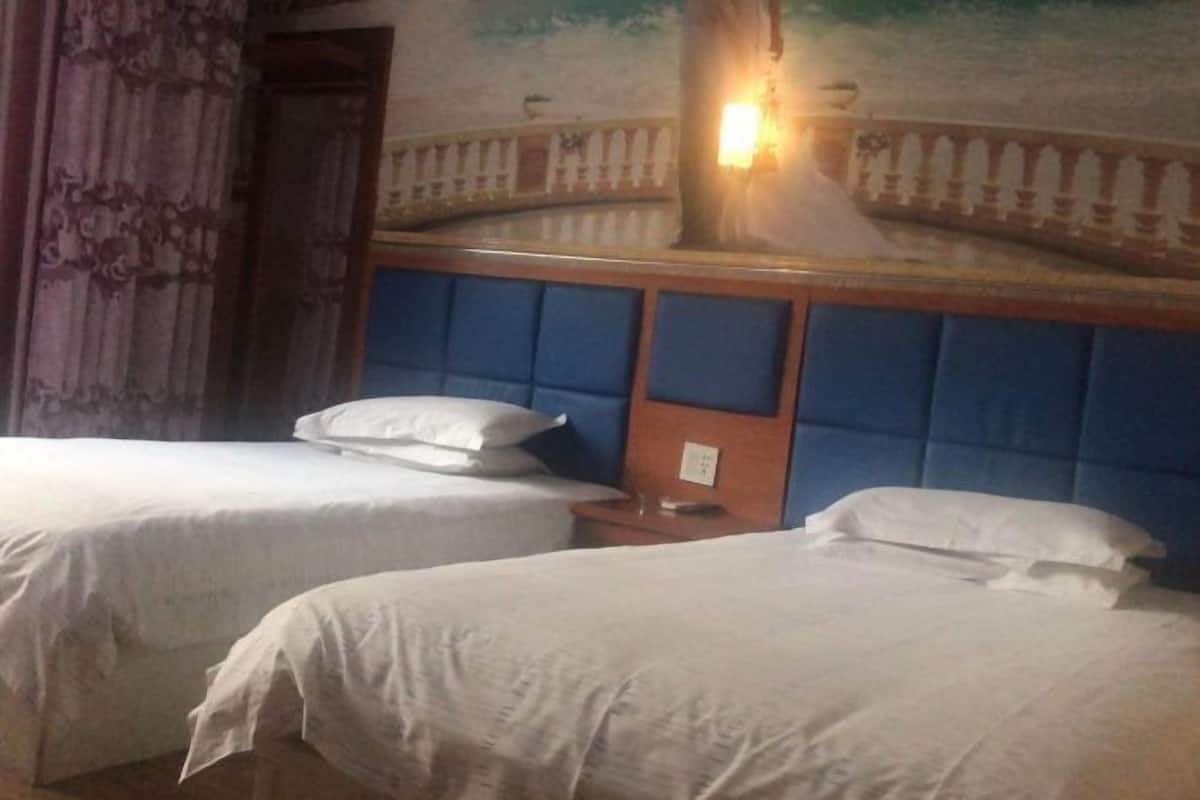 A hotel room with two beds, a nightstand, and a wall mural.