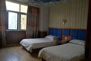 Ein Zimmer mit zwei Betten, einem Vorhangfenster, einem Kopfteil und einer Wandleuchte.