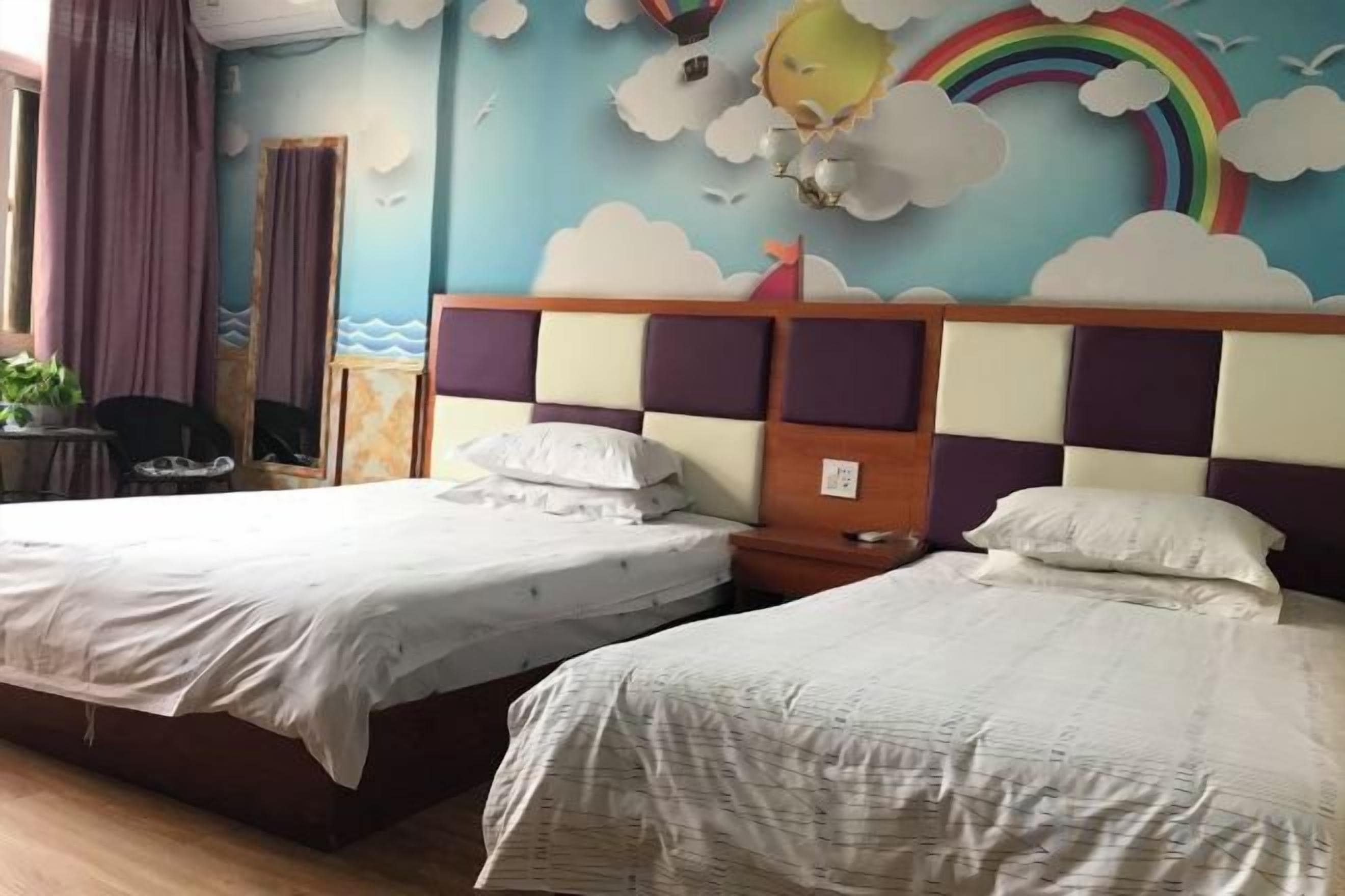 Two beds with headboards, a window with curtains, and a wall with a cloud and rainbow mural.