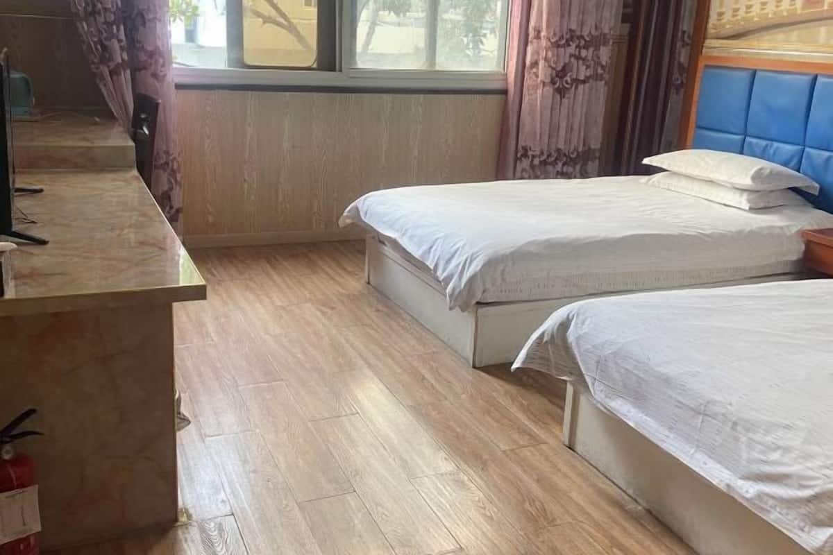A room with two beds, a desk, and a window with curtains.