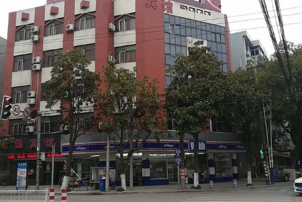 Un edificio de varios pisos con locales comerciales en la planta baja, incluyendo una farmacia y una tienda de conveniencia.