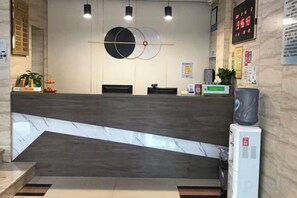 Zona de recepción con mostrador de mármol, reloj digital y dispensador de agua.