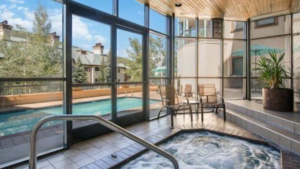 A spa area with a hot tub, seating, and a view of a swimming pool. - 2 Bedroom Residence in the Heart of Beaver Creek Village - Ski In, Ski Out (Avon)