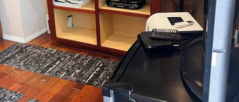 A compact kitchen with wooden cabinets, a stainless steel microwave, a coffee maker, and a refrigerator.