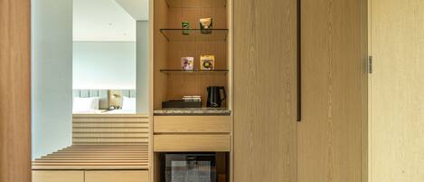 A modern hotel room with a wooden staircase, built-in shelves, and a compact kitchenette.