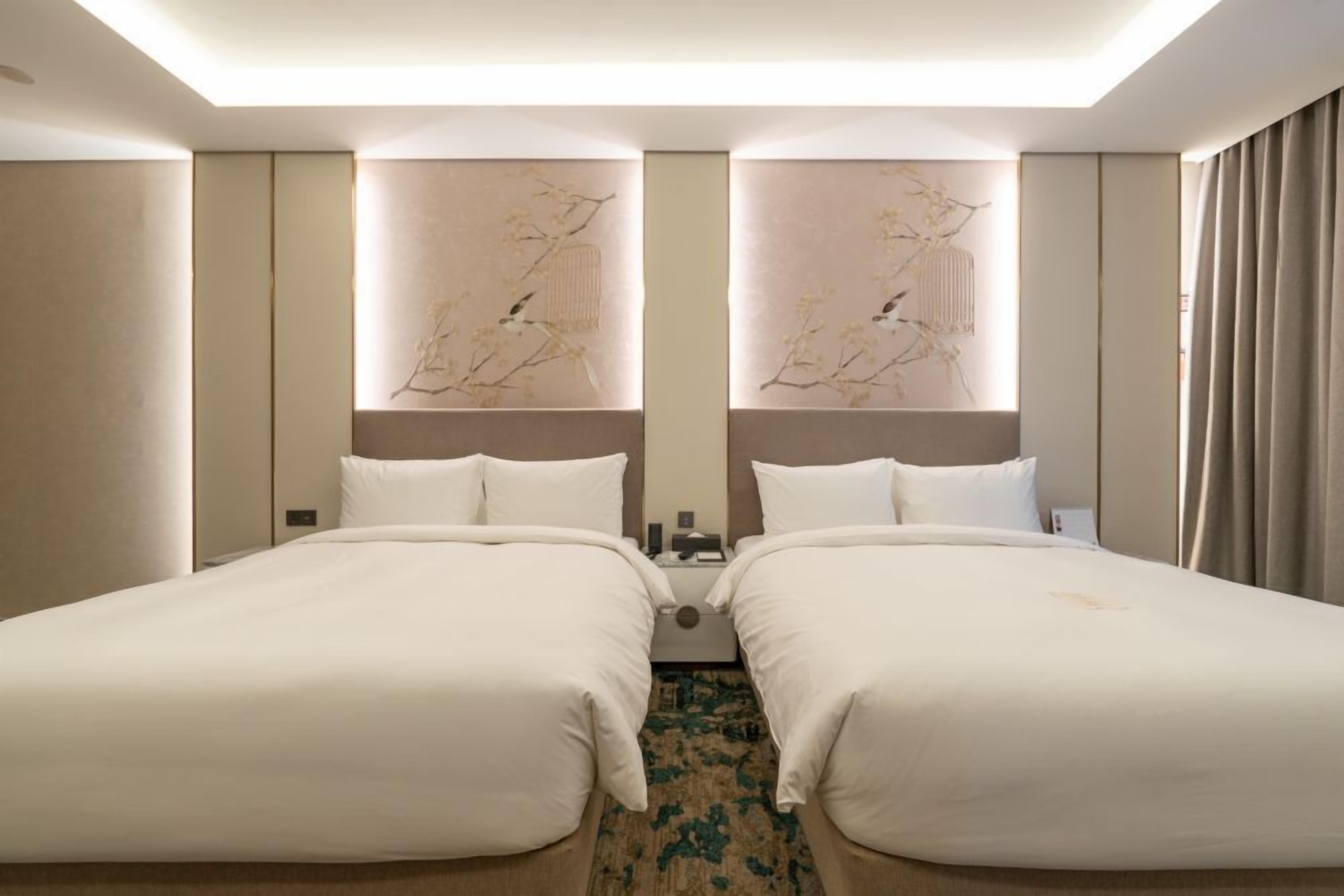 Ein Hotelzimmer mit zwei Betten, einem großen Spiegel und einem dekorativen Wandbild.