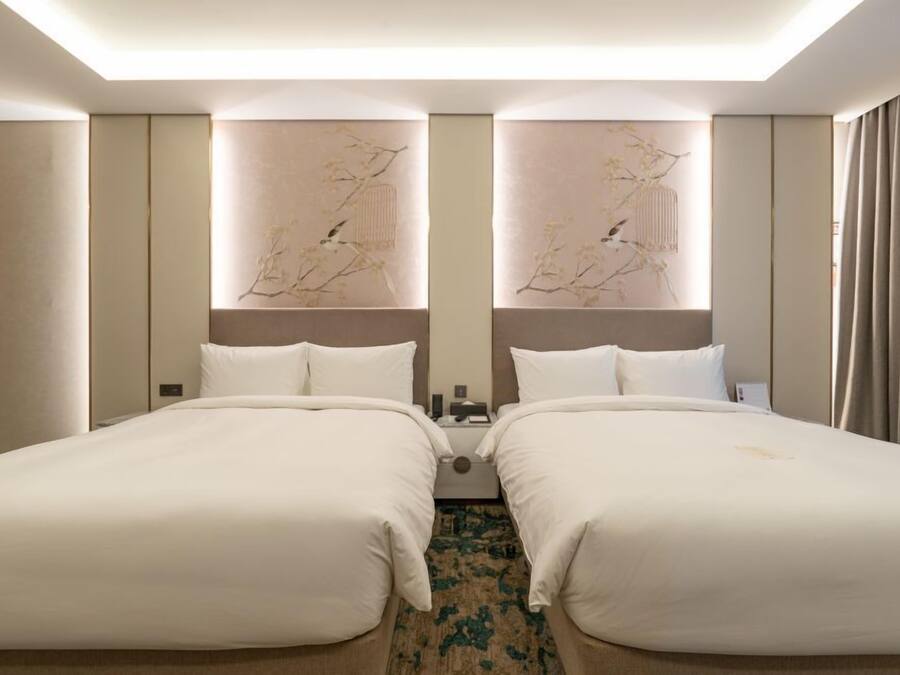 A hotel room with two beds, a large mirror, and a decorative wall piece.