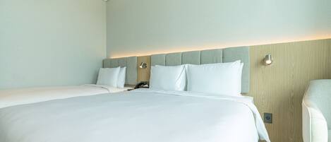 Habitación de hotel con una cama grande, una mesita de noche, una silla y una lámpara fijada a la pared.