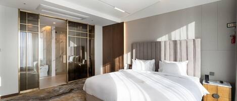 A modern hotel room with a large bed, a walk-in closet, and a marble-patterned floor.