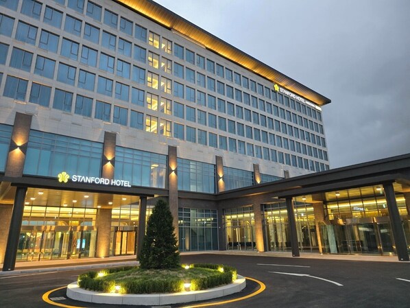 A modern hotel building with a glass facade, multiple floors, and a well-lit entrance.