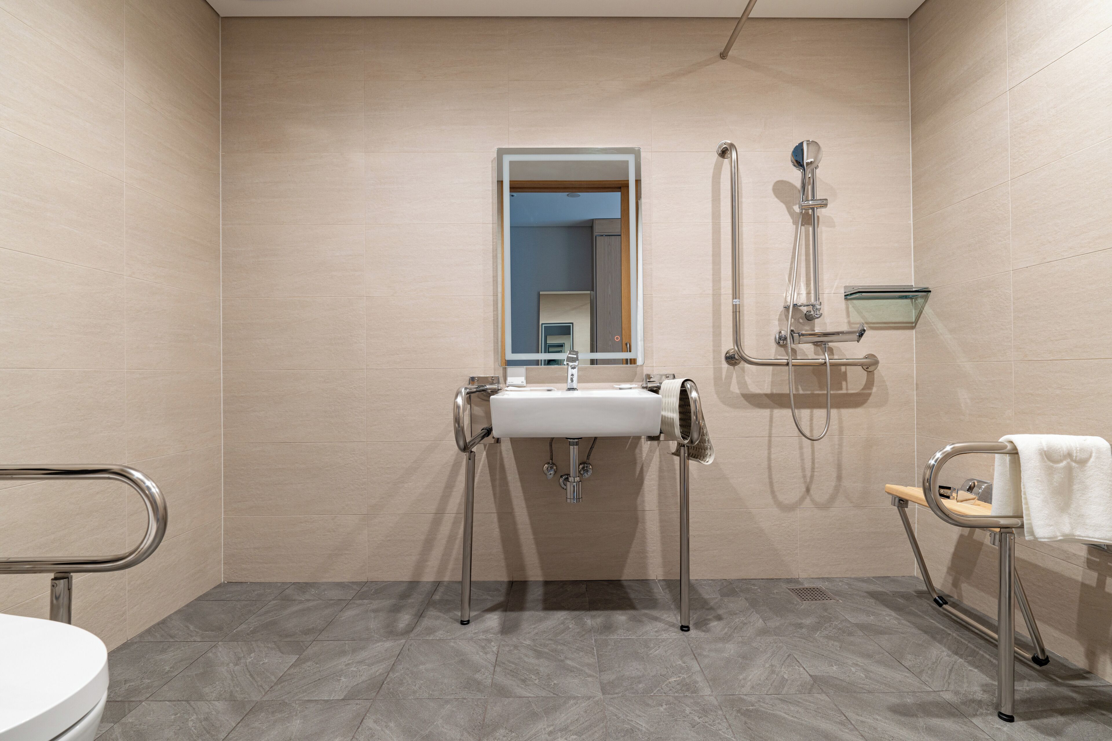 Ein modernes Badezimmer mit Waschbecken, Spiegel, Dusche und Handtuchhalter.