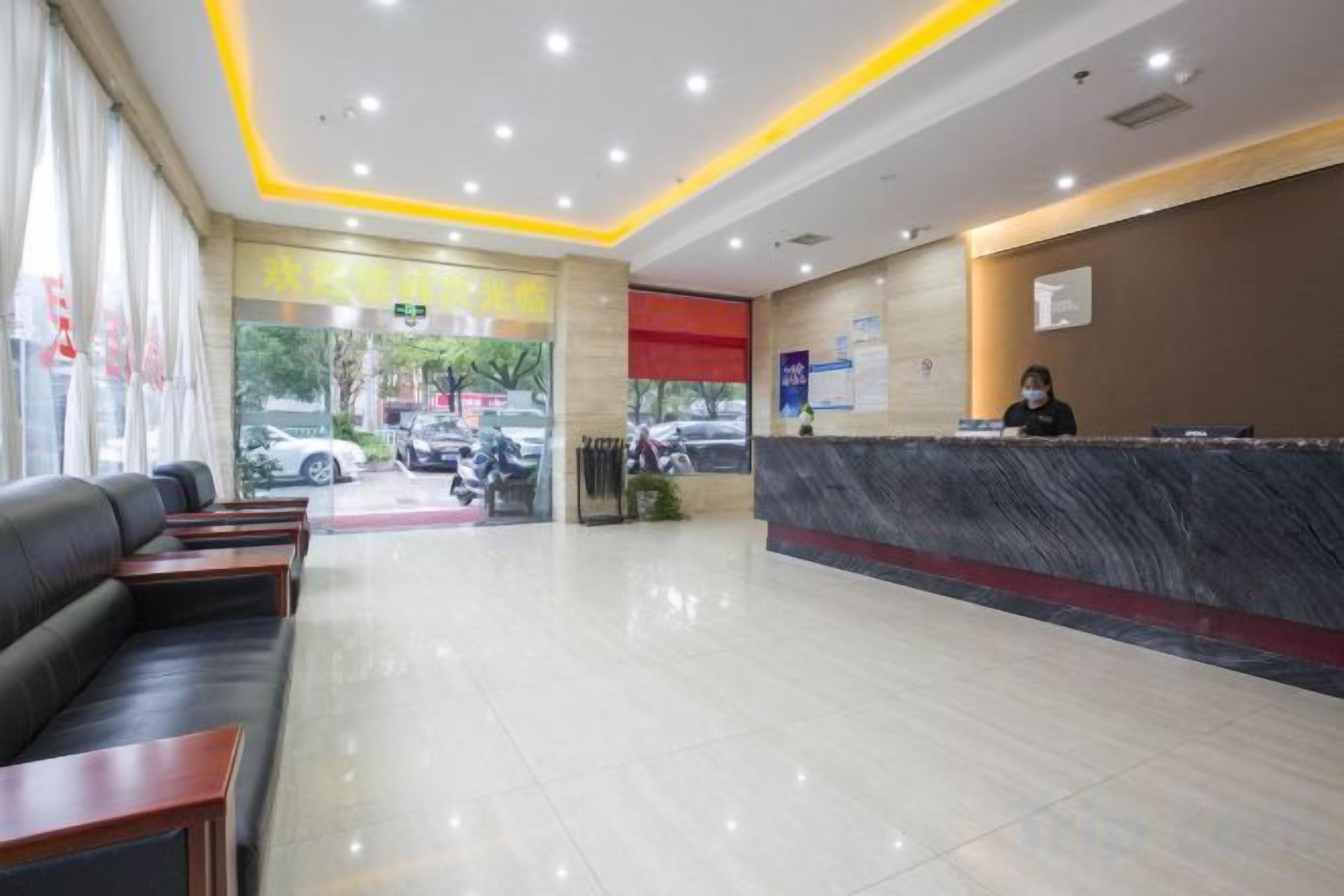 Un hall d’hôtel comprenant un comptoir d’accueil, un espace salon et une vue sur la rue.