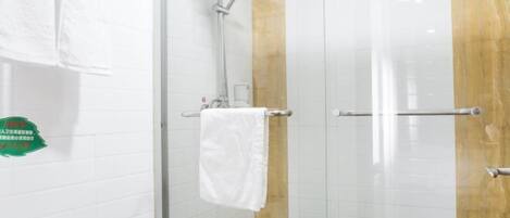 Un baño con cabina de ducha de vidrio, paredes cubiertas de azulejos blancos y un panel decorativo de madera.