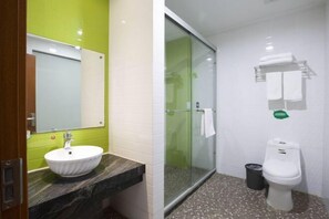 Ein Badezimmer mit einem weißen Waschbecken, einer Duschkabine aus Glas und einer Toilette.