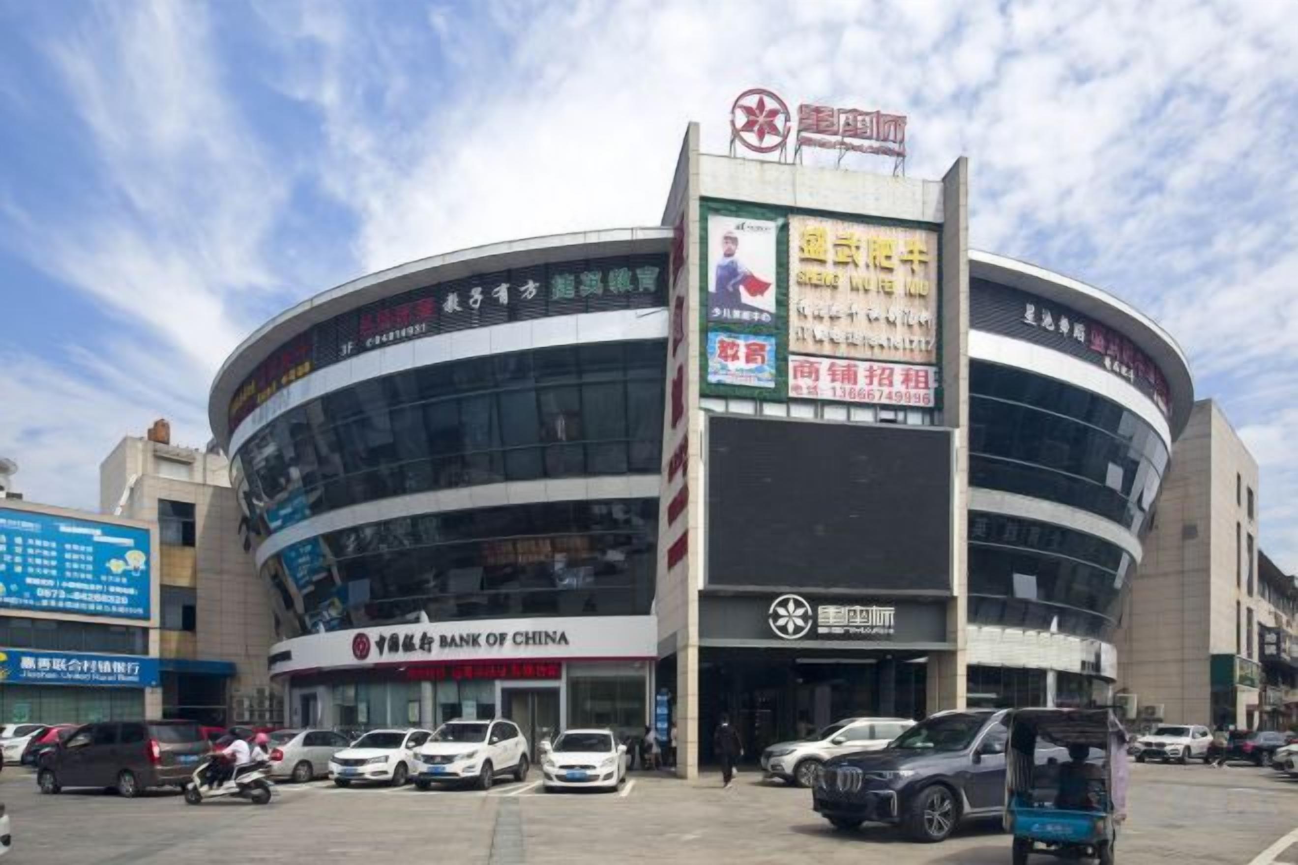 A commercial building with a curved facade, a prominent sign for Bank of China, and several parked vehicles in front.