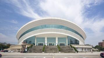 Een groot, modern gebouw met een golvend dak en meerdere ingangen.