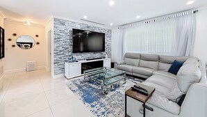 Un salon moderne avec un téléviseur à écran plat, un canapé, une table basse et un tapis à motifs.