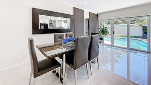 Un espace repas moderne, agrémenté d’un grand miroir, d’une table à manger et de chaises.