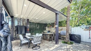 Une terrasse extérieure dotée d’un espace salon abrité, d’un barbecue et d’un mur décoratif.