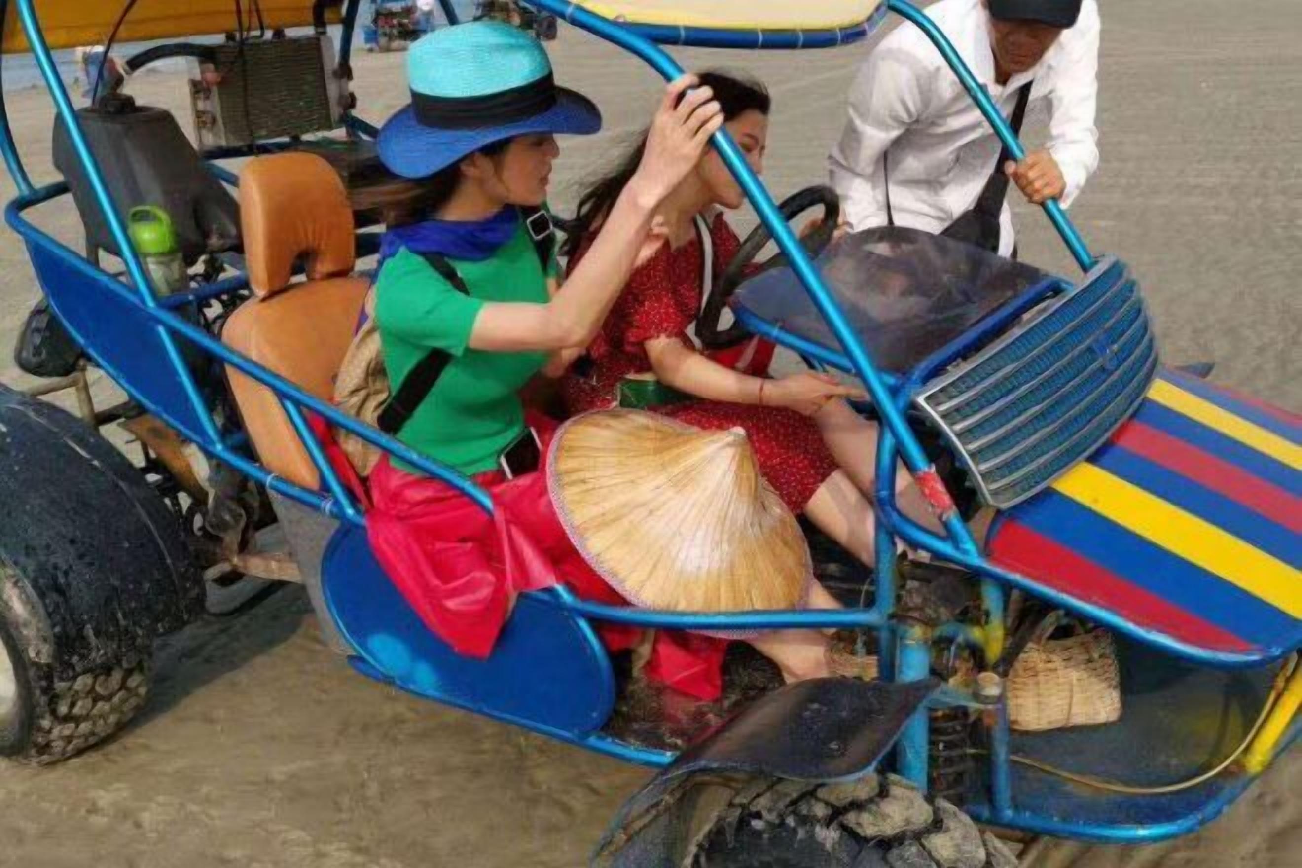 A group of people in a colorful, enclosed vehicle with a roof, possibly a rickshaw, on a sandy surface.