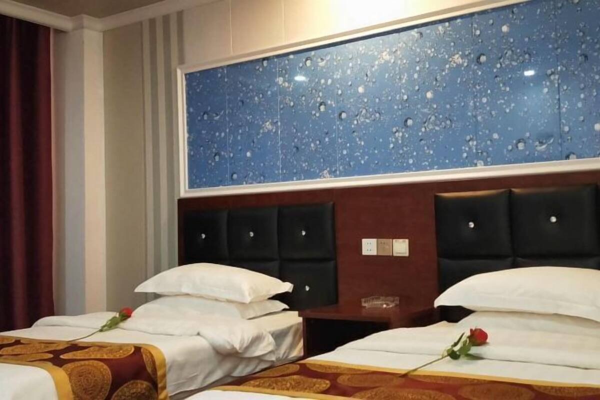 A hotel room with two beds, a large blue wall with water droplets, and a red curtain.