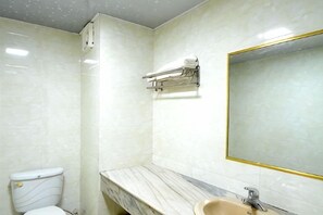 Un baño con inodoro, lavamanos, espejo y toallero.