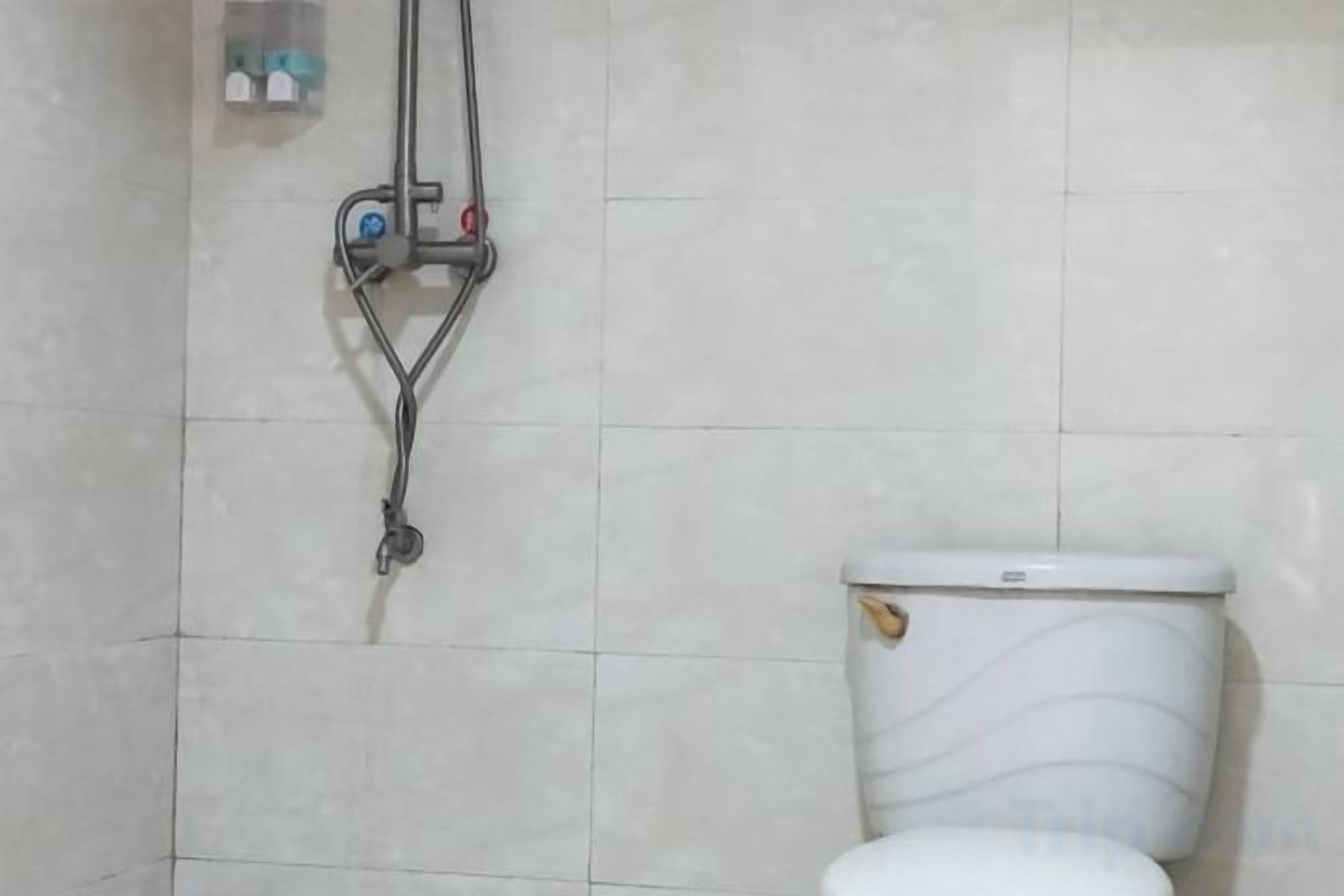 Une salle de bain équipée de toilettes, d’une douche et d’une petite étagère où sont rangés les articles de toilette.