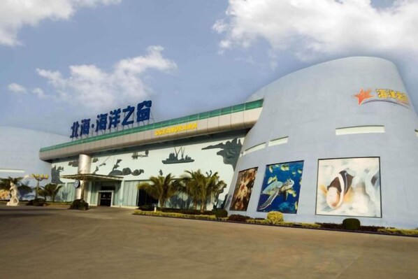 A building with a curved facade, a large entrance, and a sign with Chinese characters. - Beihai Jiajia Hotel (Beibuwan Square Branch) (Beihai)