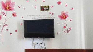 A flat-screen TV mounted on a wall with decorative floral stickers and a small sign above it. - Beihai Jiajia Hotel (Beibuwan Square Branch) (Beihai)