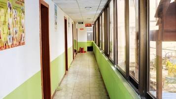 Un pasillo con puertas a la izquierda y ventanas a la derecha.