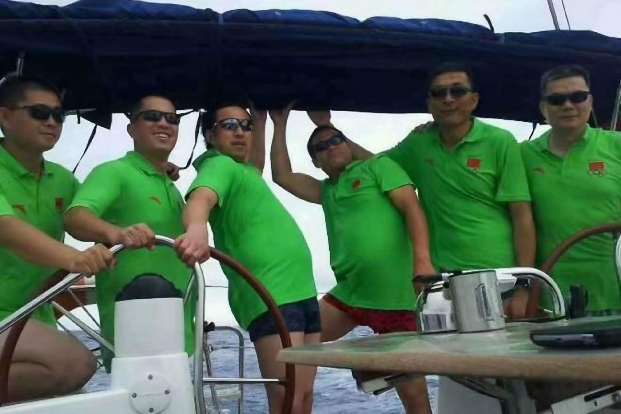 Eine Gruppe von Menschen auf einem Boot mit Steuerrad und Metallgeländer.