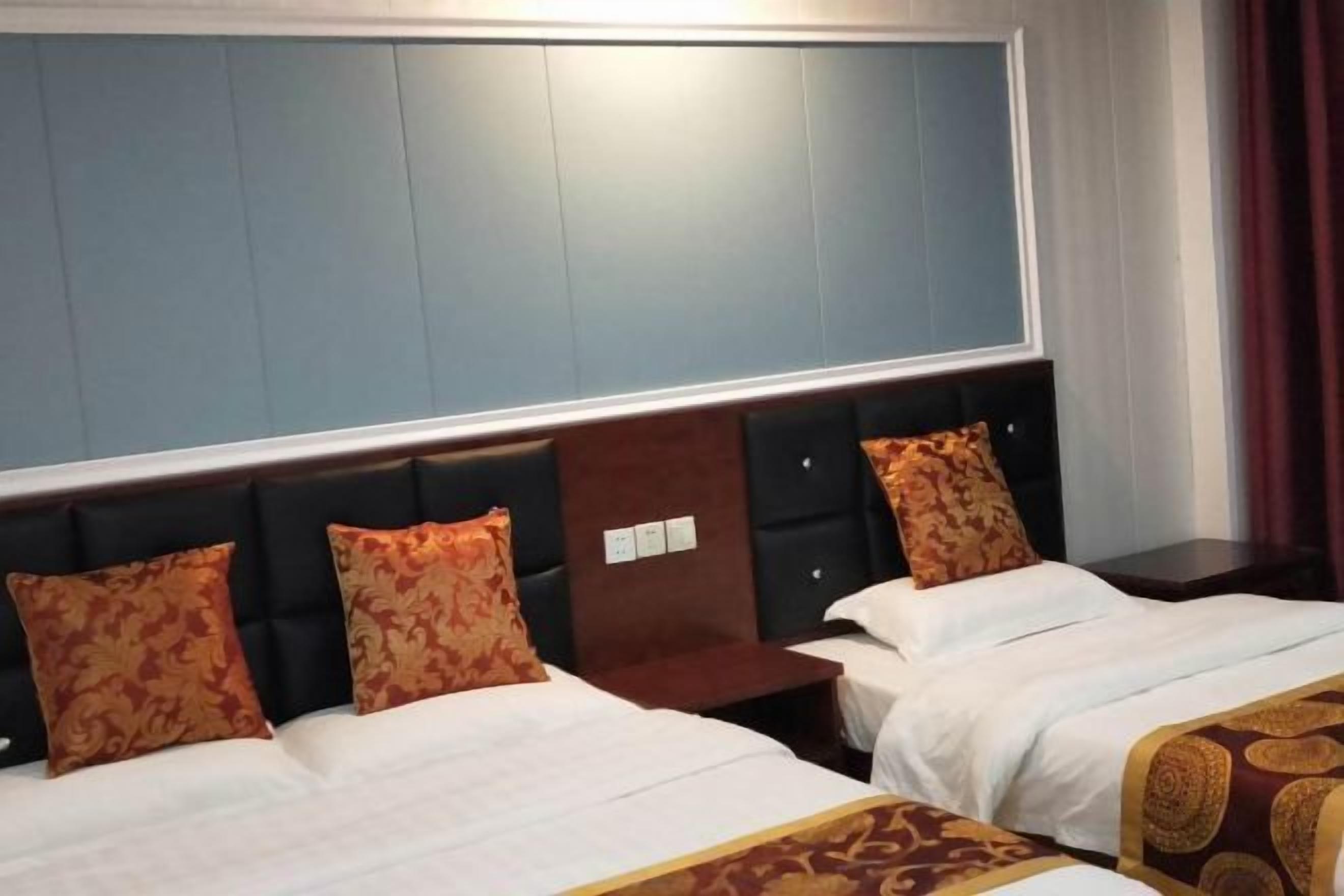 A hotel room with two beds, a large window, and a dark headboard.