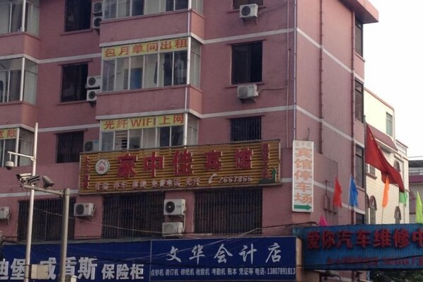 Un edificio de varios pisos con diversos comercios en la planta baja, incluyendo un letrero visible de un negocio y un taller de reparación de vehículos.