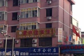 A multi-story building with various commercial establishments on the ground floor, including a visible sign for a business and a vehicle repair shop. - Beihai Jiajia Hotel (Beibuwan Square Branch) (Beihai)