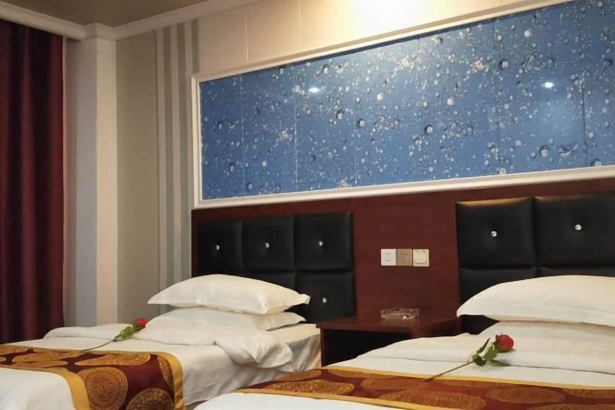 A hotel room with two beds, a large blue marble headboard, and a red curtain.