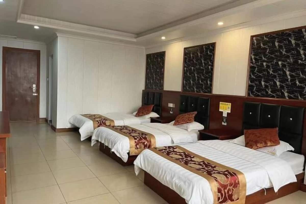 A hotel room with three beds, each with a headboard and a decorative panel above.