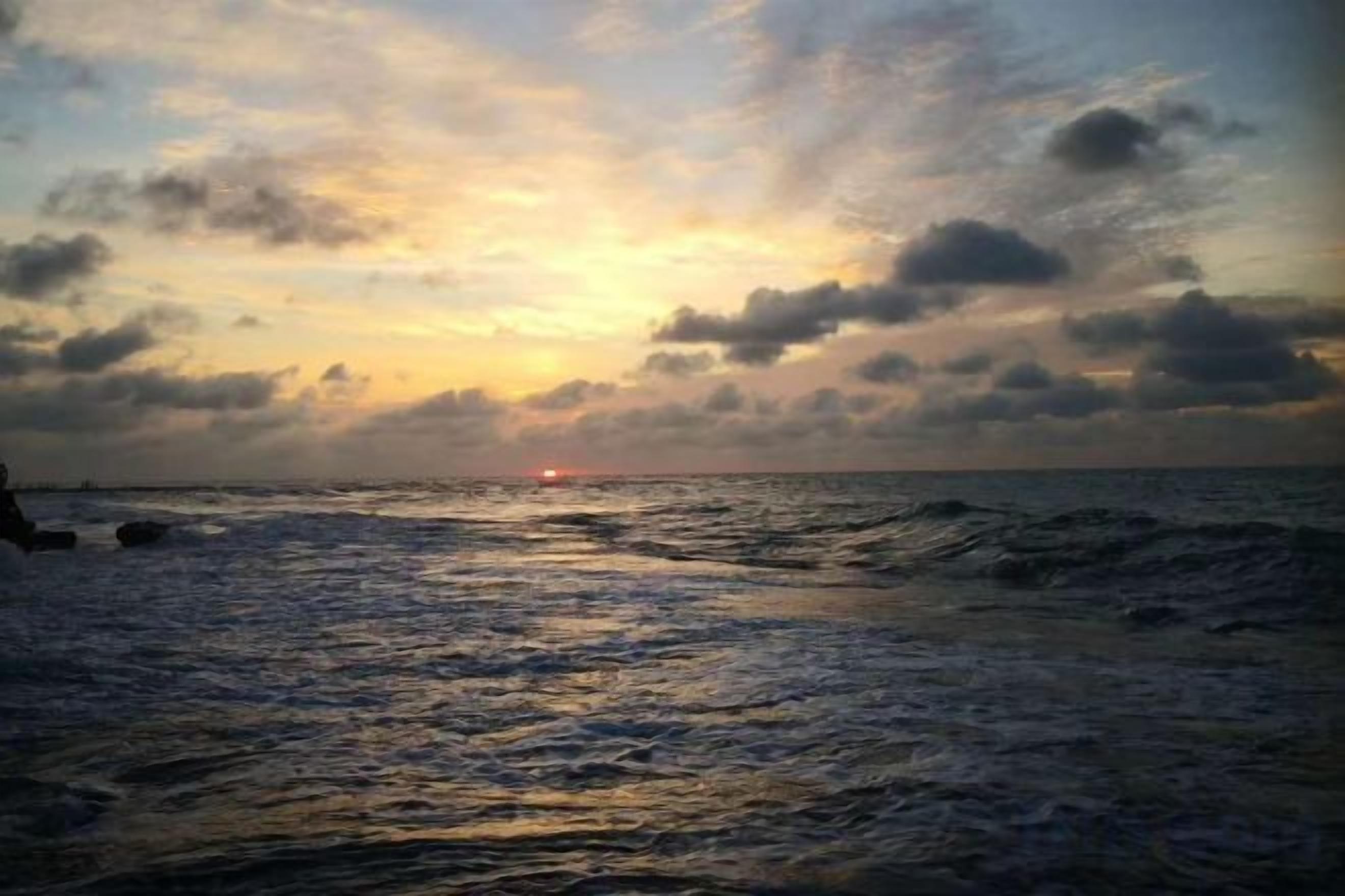Ein Sonnenuntergang über dem Meer mit Wellen.