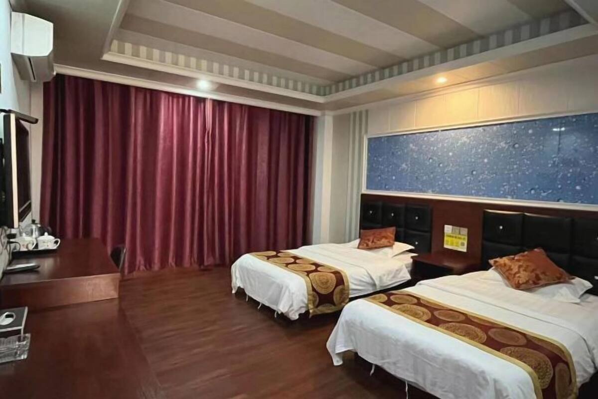 A hotel room with two beds, a desk, and a large window.