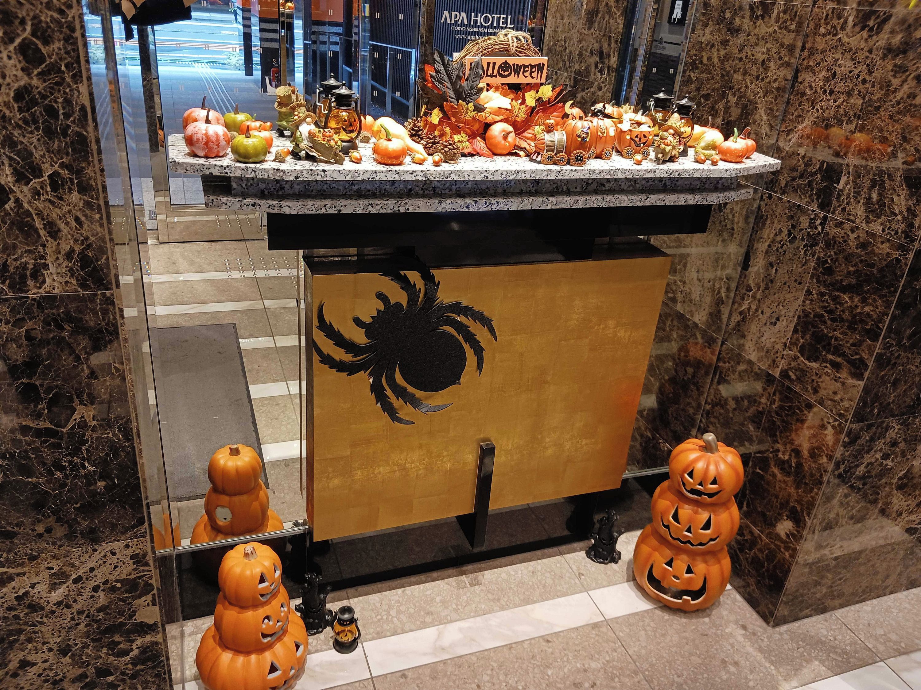 A hotel reception area with a Halloween-themed display including pumpkins and autumn leaves.